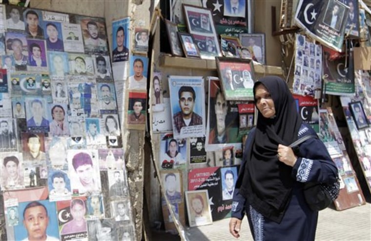 A Libyan woman walks past portraits of people killed or who have disappeared during the rule of Libyan leader Moammar Gadhafi's regime at the court square in the rebel-held capital Benghazi, Libya.